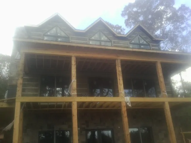 Dormers and porch framing on a large log home under construction — Roof Coating work by our crew in Dell Rapids