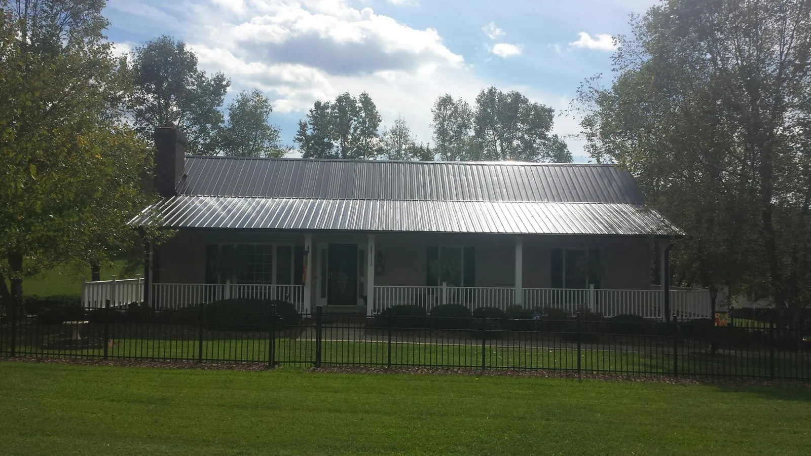 Gray metal roof on a brick ranch with a full width front porch — Gutter Guard Installation work by our crew in Dell Rapids