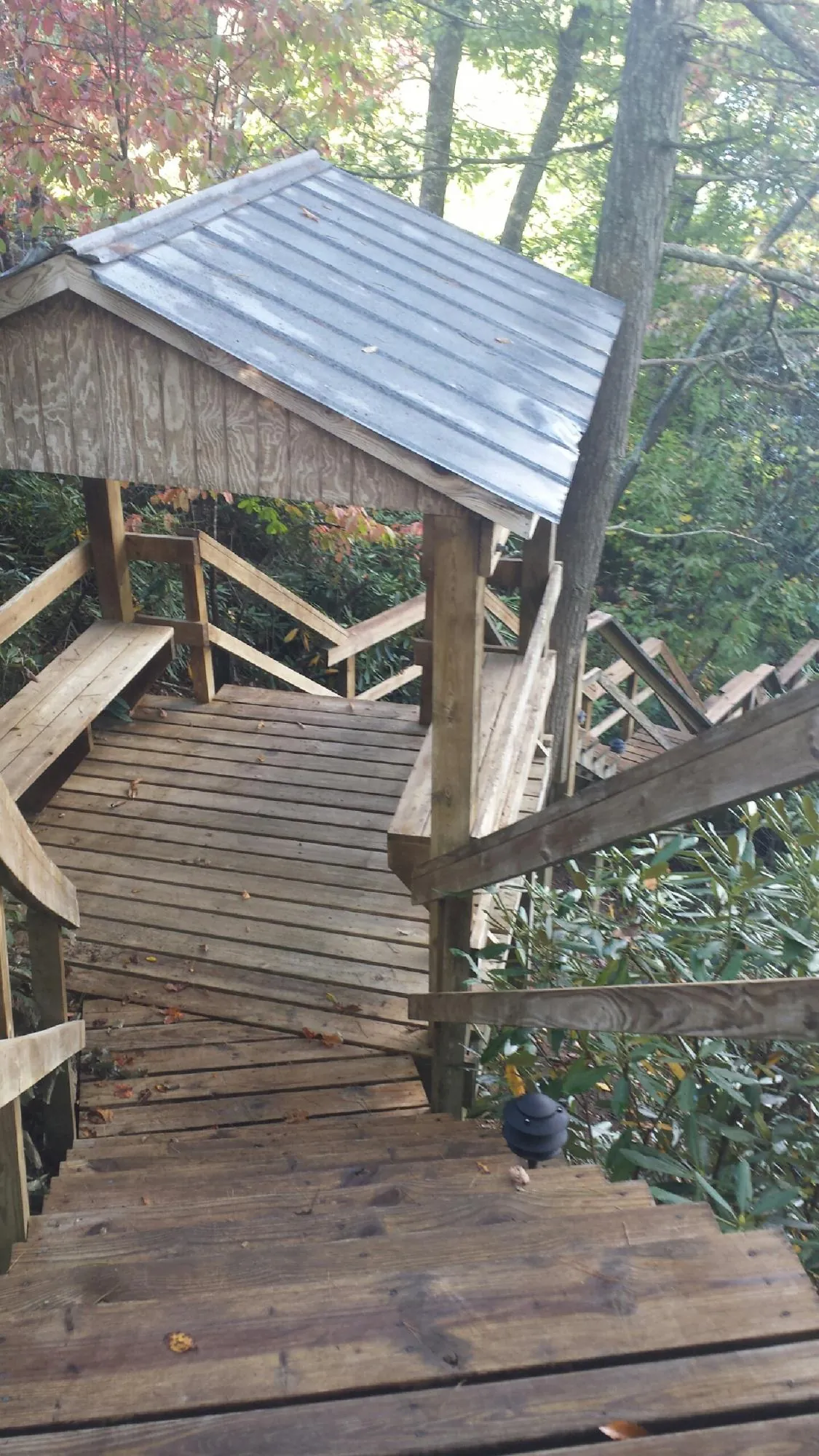 Metal roofed shelter over wooden steps on a wooded walkway — Skylight Repair & Installation work by our crew in Dell Rapids