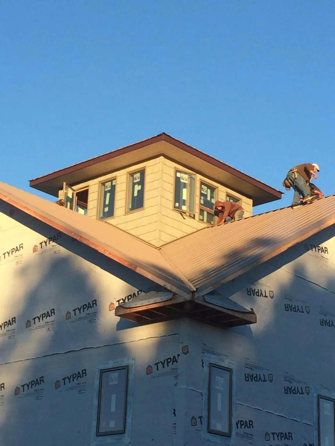Roofers working around a rooftop cupola on a new metal roof at sunset — Roof Waterproofing in Dell Rapids by Roofing Brothers